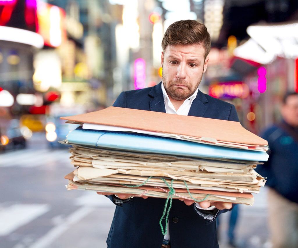 Un'azienda paperless è ecosostenibile, è libera da ogni archivio materiale, fatto di cartelle ingombranti e scartoffie. Nella foto, un dipendente d'ufficio che porta delle pesanti cartelle.