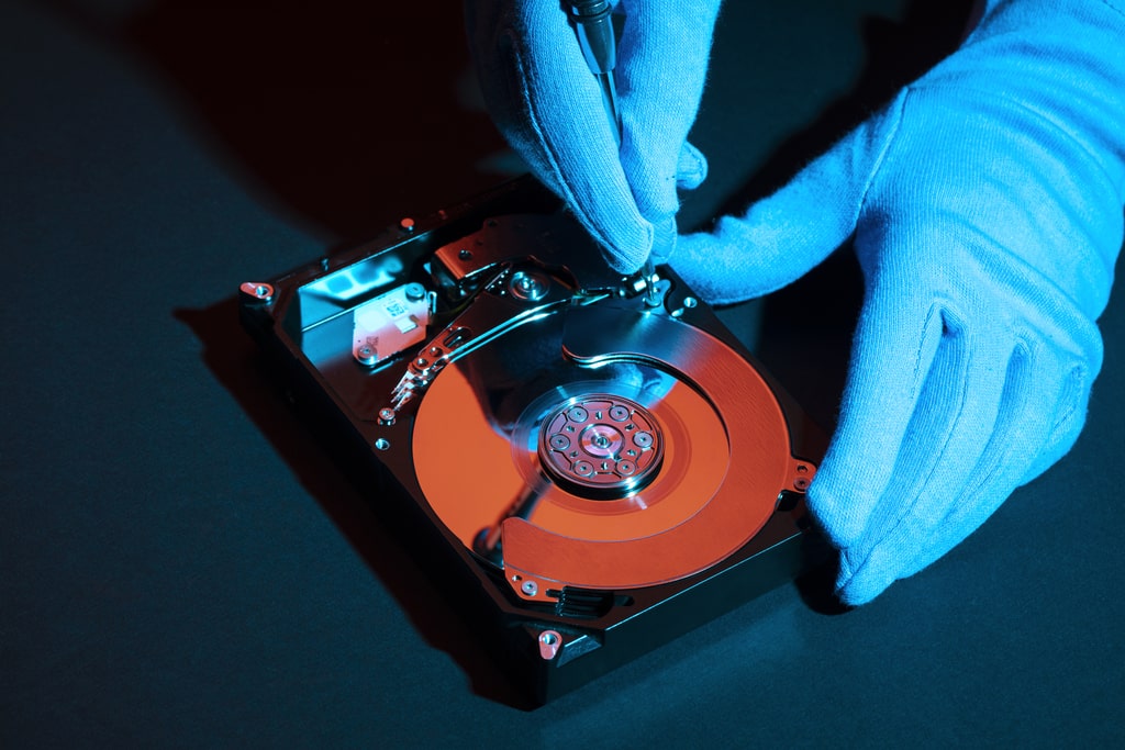 Prima ancora di ripararlo, è importante imparare come prevenire il danneggiamento dell'hard disk del proprio computer in modo da evitare perdite di dati. Nella foto, un tecnico che ripara un disco rigido.